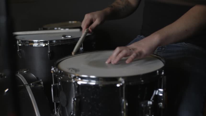 A man picks up a drum stick and taps his drums