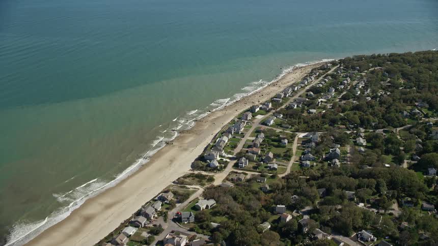 An aerial of a wooded residential neighborhood along an ocean shore