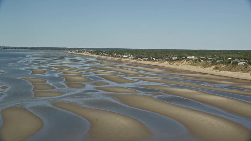 A beach with the sea receding andleaving only puddles of water
