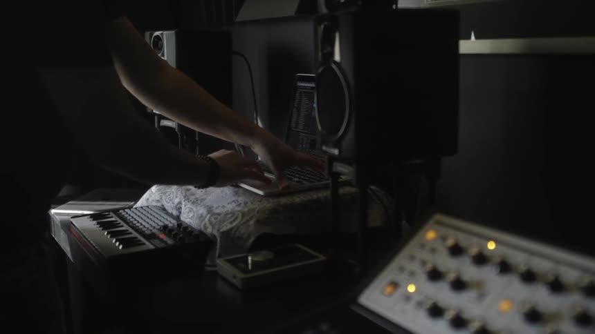 A man is using a laptop near musical equipment