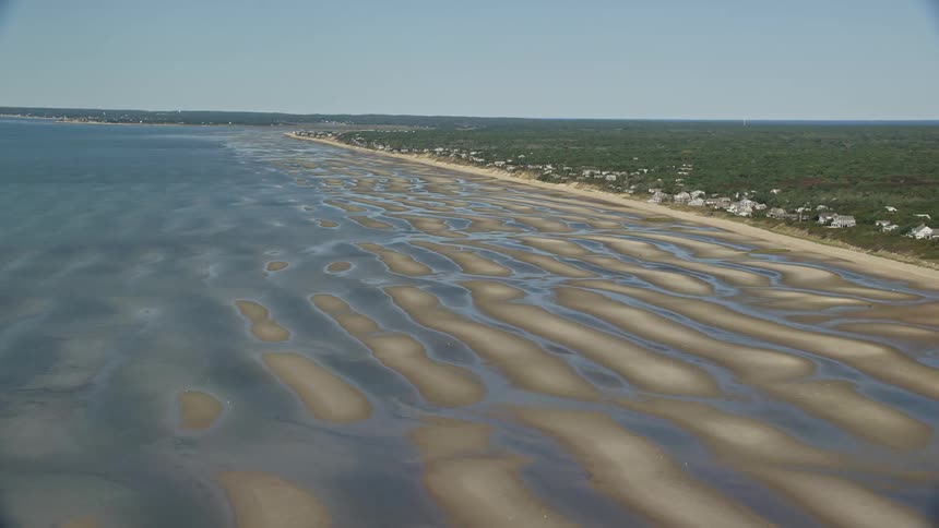 Sand bars along the beach at low tide near a coastal town