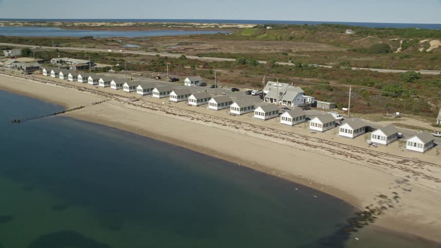 Cottages line the coast along the beach as traffic moves on the street