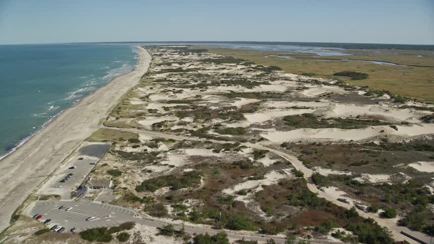 Dirt roads wind through terrain bordering beach near town