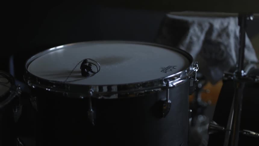 Earbuds sit on a single drum in a dark room