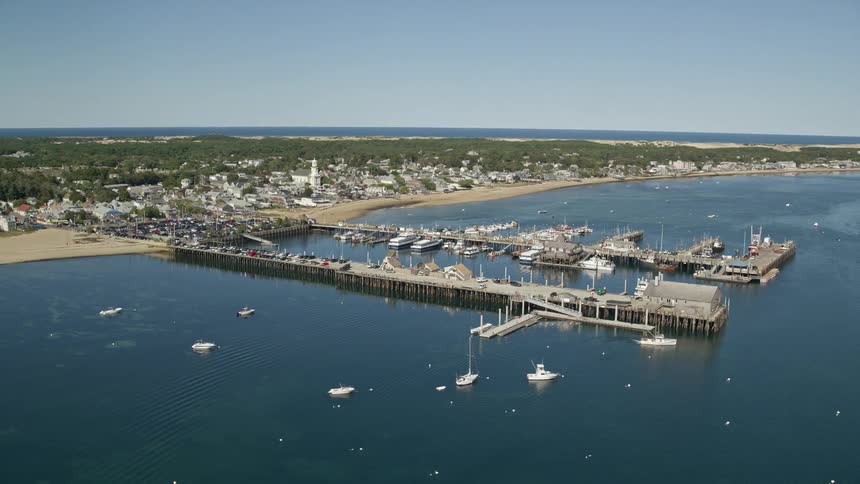 A coastal region of an island with a city and a huge pier with several boats