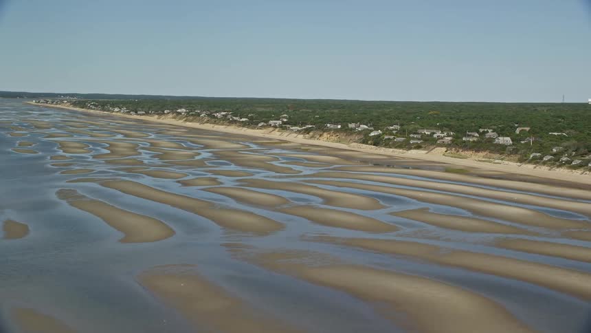 Aerial view of sand banks on the coast next to a town