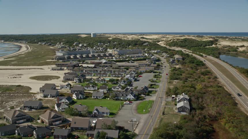 Traffic moves on highways alongside a coastal community as waves roll into shore
