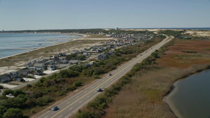 A large highway passing through an area with houses surrounded by the sea