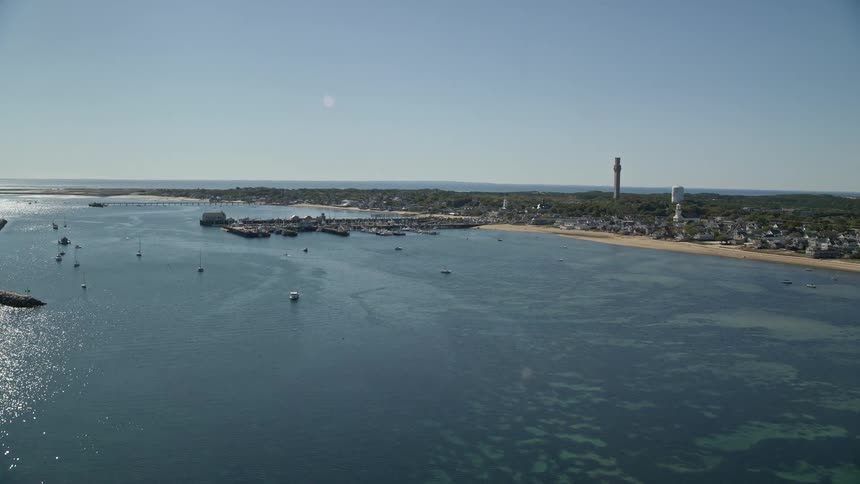 Boats float off shore near coastal town on sunny day