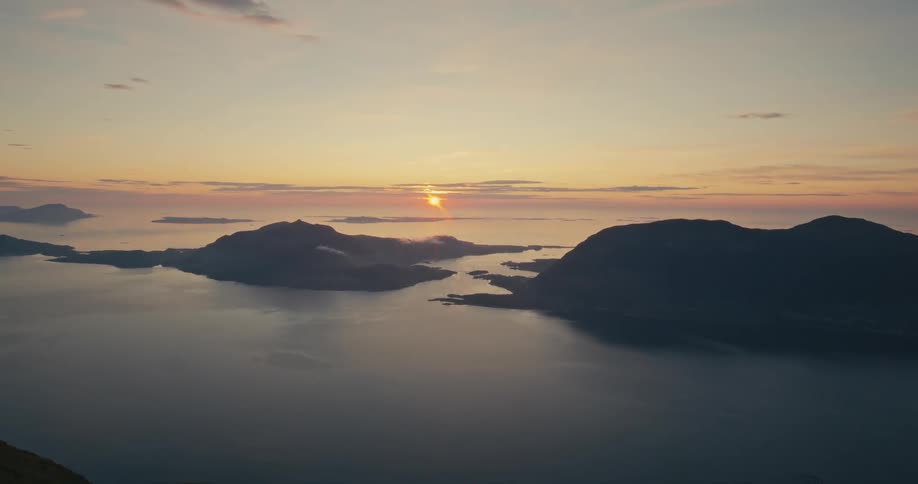 A landscape of two mountains surrounded by the sea and a sunrise