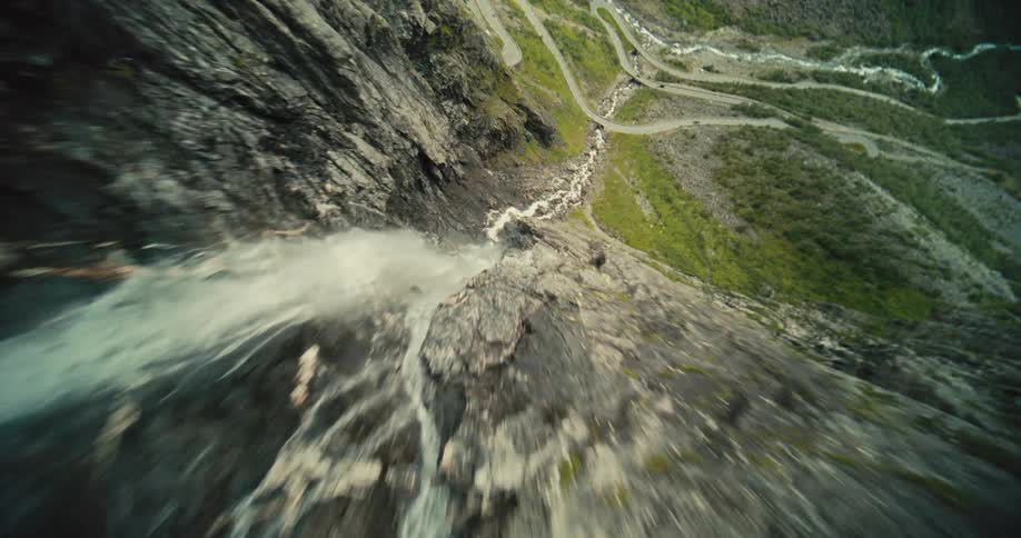 A rocky mountain with a valley of falling water running all the way down