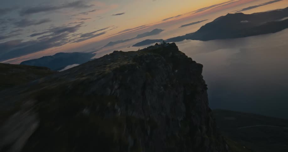 Aerial drone view of the slopes of a mountain next to the ocean at sunset