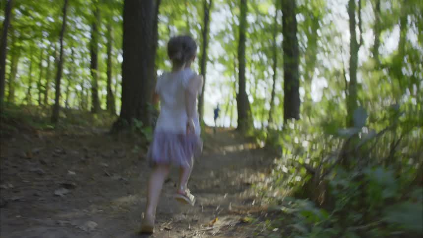 Little girl chases her brother on a forest at morning