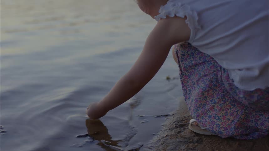 Boy and girl playing outdoors next to a river at Sunset