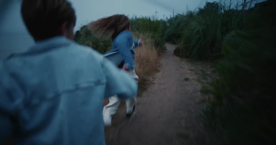 Two teen running on a path surrounded with tall grasses