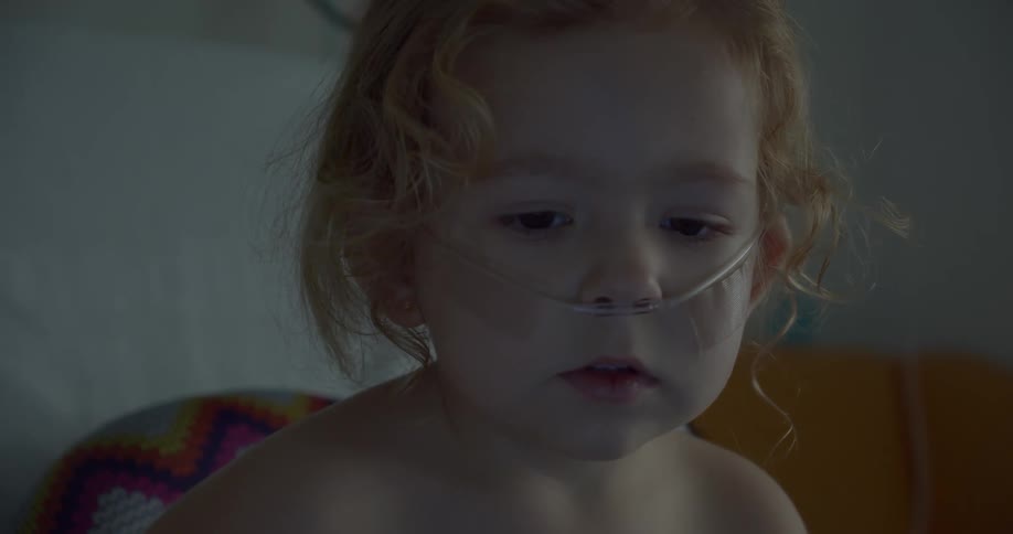 A child without a shirt on is wearing a nasogastric tube