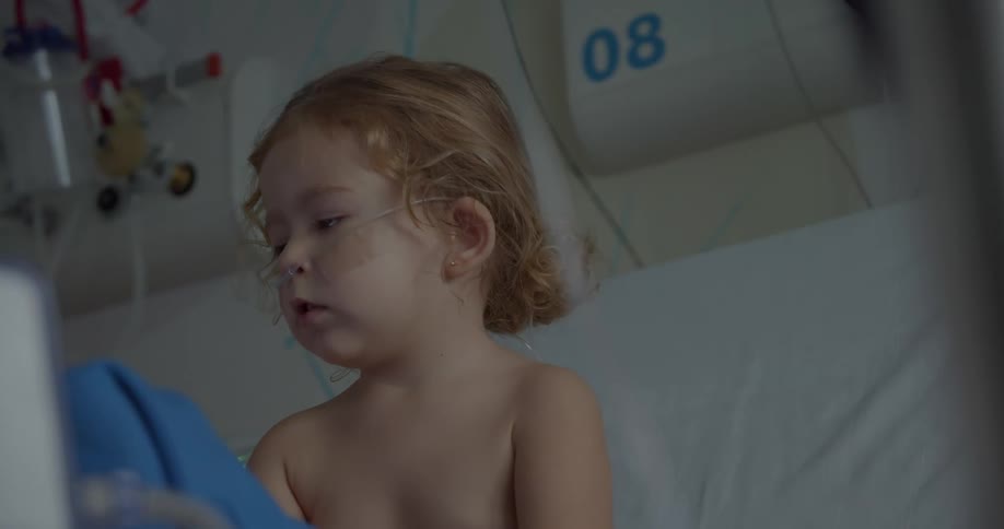 A child sitting on an hospital bed without a shirt on