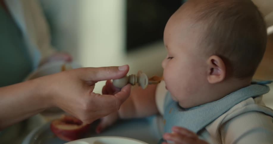A person feeding a baby sitting in a car seat