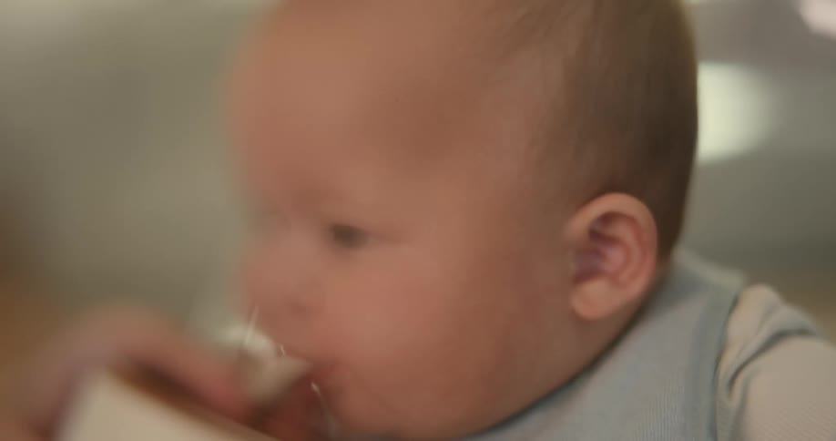 Parent feeds baby sitting in baby chair laughing