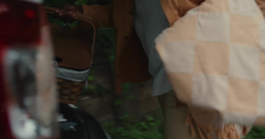An adult man wearing glasses placing a basket of food in the trunk of a car