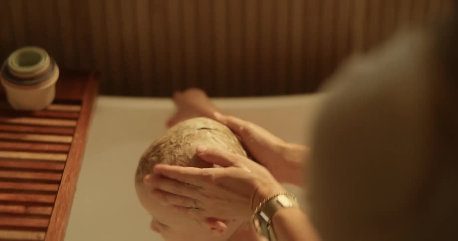 Mother bathing her son in a bathtub indoor