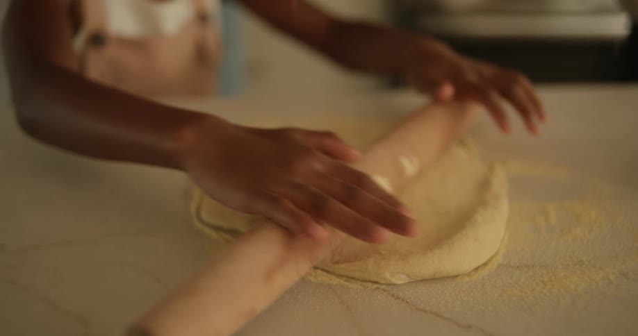A little girl kneading dough using a steamroller