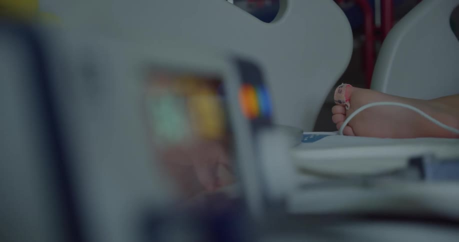 A child laying on the hospital bed with a heart monitor