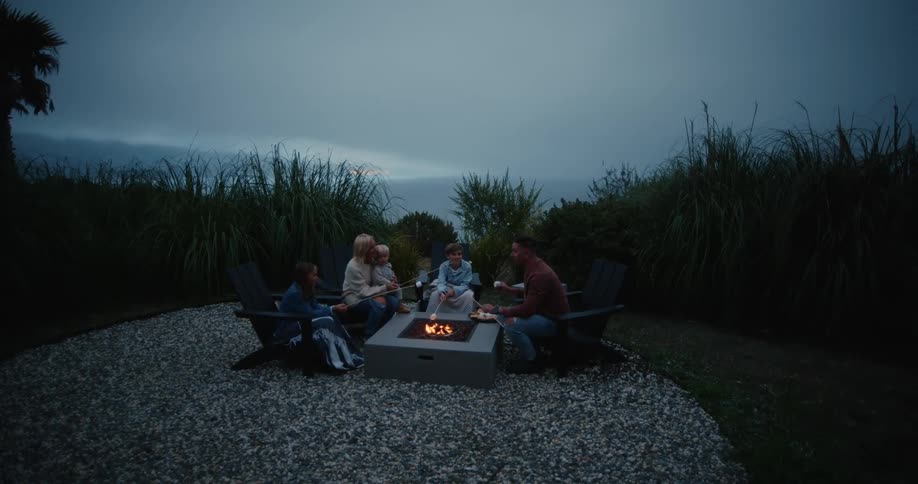 A family gathered around a campfire eating marshmallows