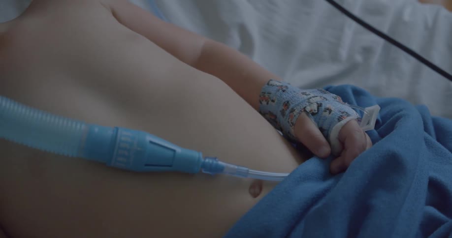 Child lying on a hospital bed with a small tube in their body