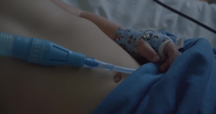 Young child lies in hospital bed with an oxygen feed