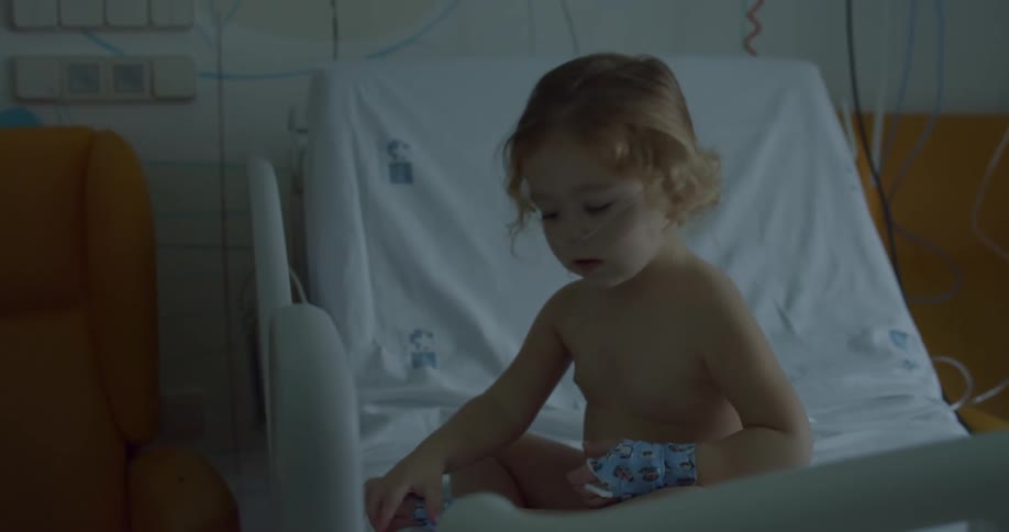 A little girl sitting in the hospital bed playing with the hospital controls