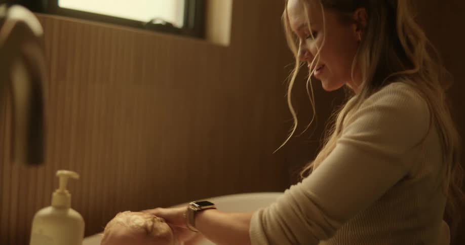 A happy mother playing with her son who is bathing in the bathtub