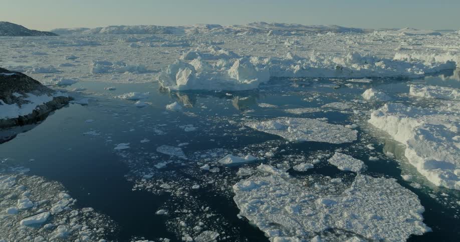 Aerial of the sea with ice and frozen mountains during the day