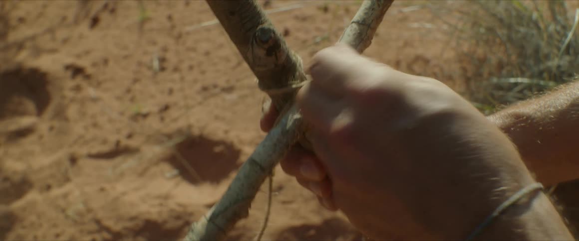 Hands of a person tying two pieces of wood together