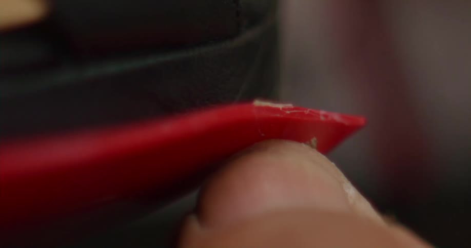 Person shapes thin red strip with a fingernail