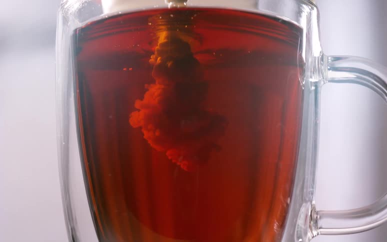 Milk being poured into tea in a glass