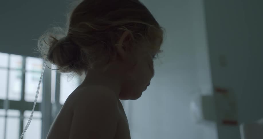 A little blonde girl with a nasal catheter inside a room