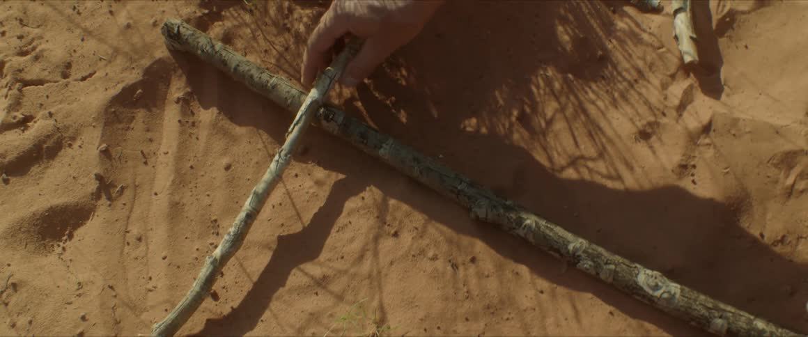 Man crafts a rudimentary cross using sticks