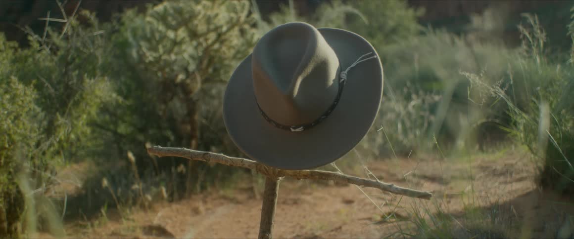 Cowboy hat hanging from a makeshift cross made with sticks
