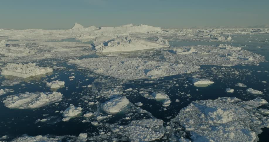 Panorama of a sea with some frozen parts and arctic icebergs
