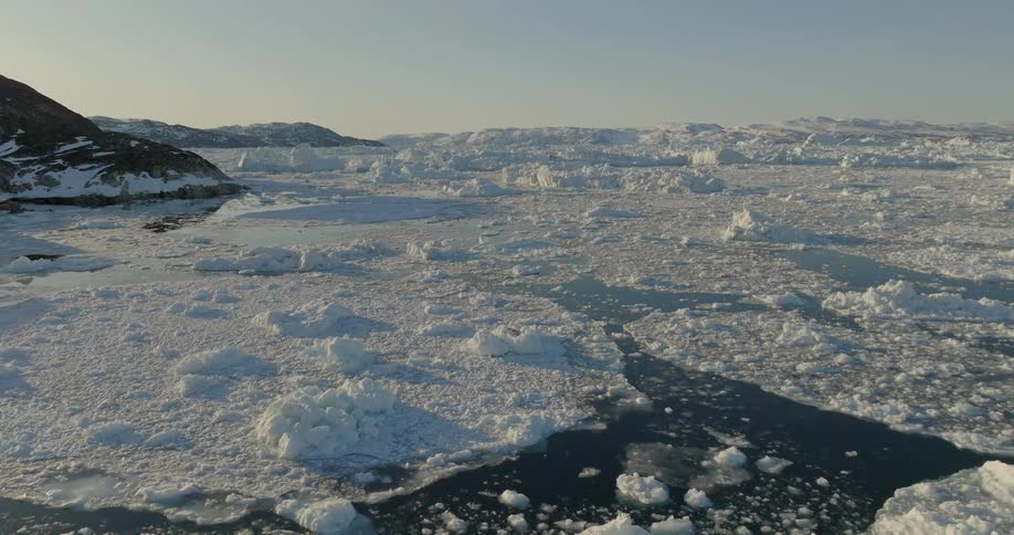 Aerial landscape of icy region with water and hills during dusk or dawn