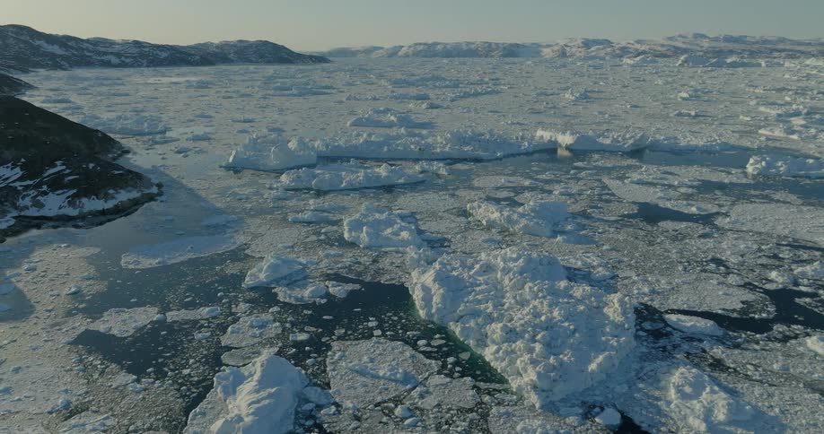 Artic ice melting in the sea near a rock on a sunny day