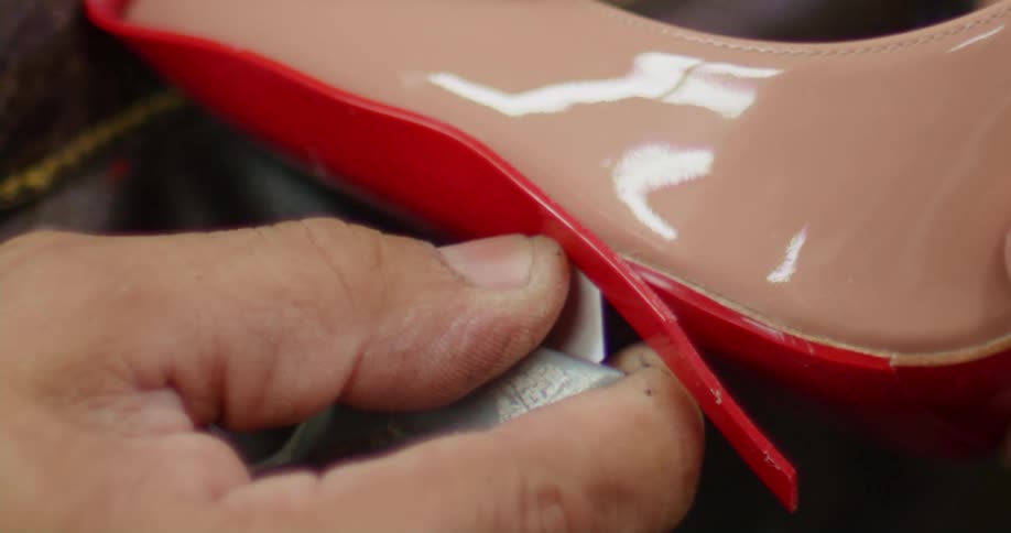 Shoemaker uses a knife to cut the sole of a shoe