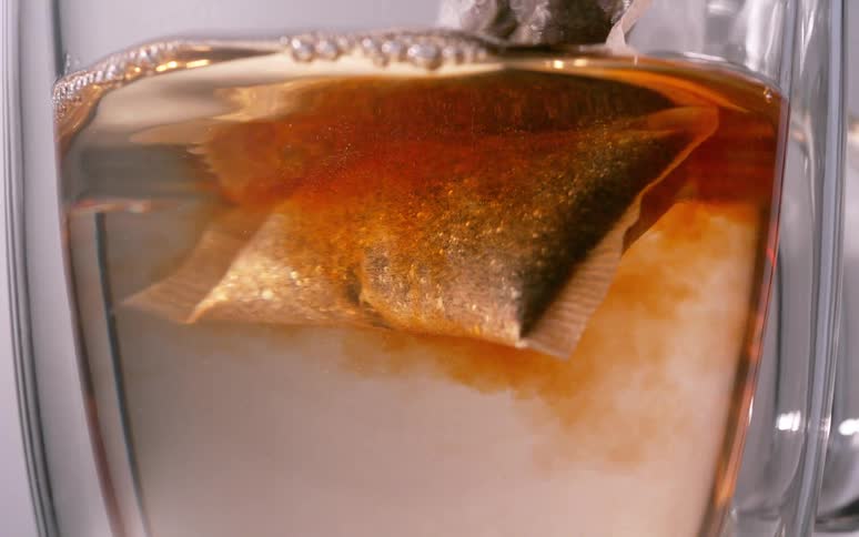 A closeup shot capturing a tea bag steeping inside a transparent glass