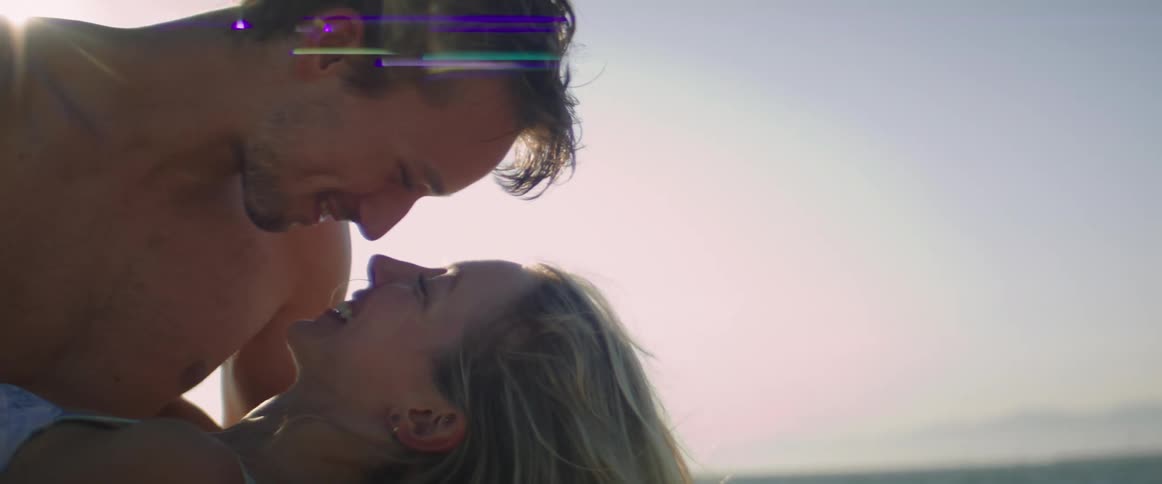 Sun glares down on man dipping woman back and kissing her