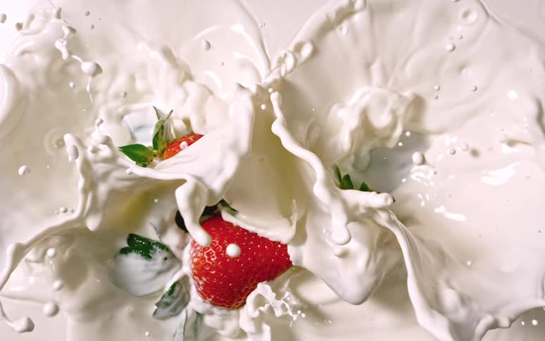 Strawberries falling into milk in slow motion