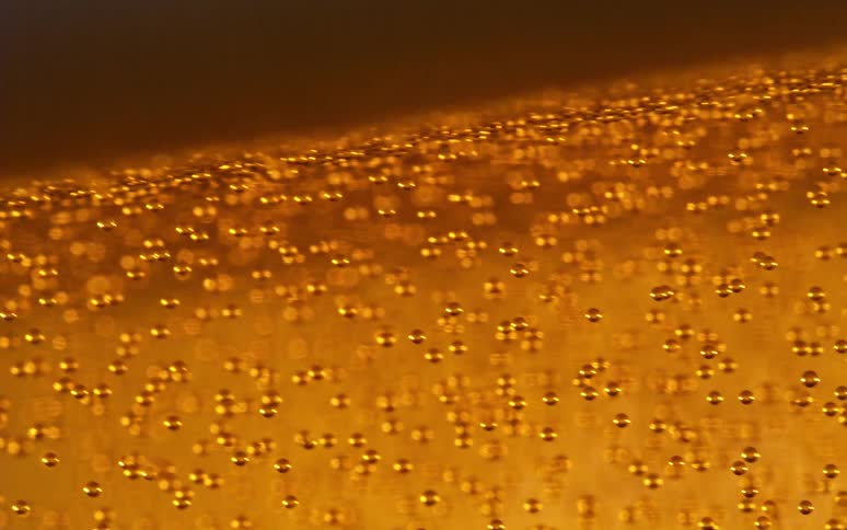 Air bubbles trapped inside a thick yellow golden liquid
