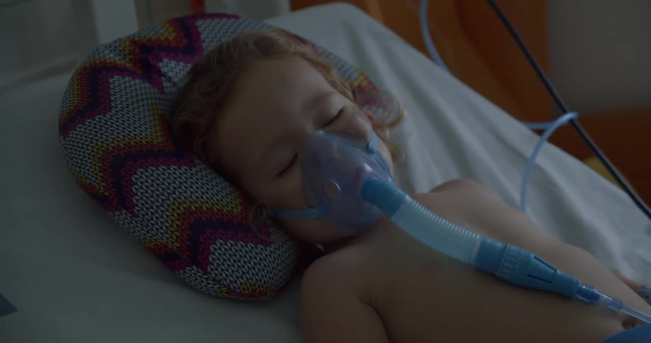 Little blonde girl hooked to a respirator in the hospital