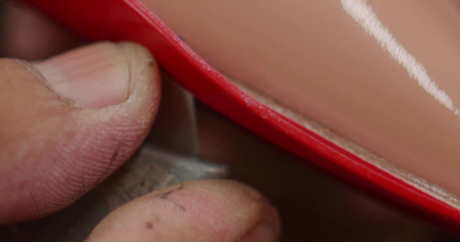 Persons finger engaged in manufacturing work on red fabric