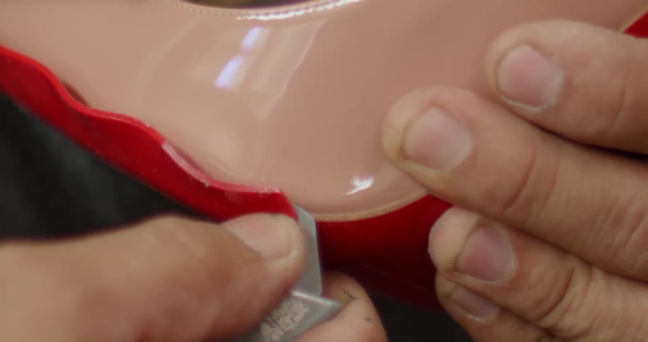 A persons hands cutting a material with a utility knife